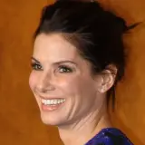 Sandra Bullock 2024: Uśmiechnięta aktorka z błyszczącymi oczami i upiętymi włosami, na tle logotypów TBS i TNT.