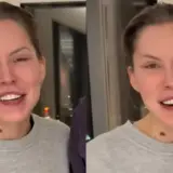 Uśmiechnięta Julia von Stein w szarej bluzie, z charakterystycznym znamieniem na szyi.