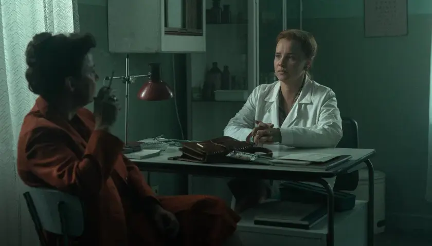 Dwie kobiety w gabinecie lekarskim. Jedna w białym kitlu, druga w pomarańczowym płaszczu, pali papierosa. Czy to scena z filmu "Ołowiane dzieci" czy na faktach?