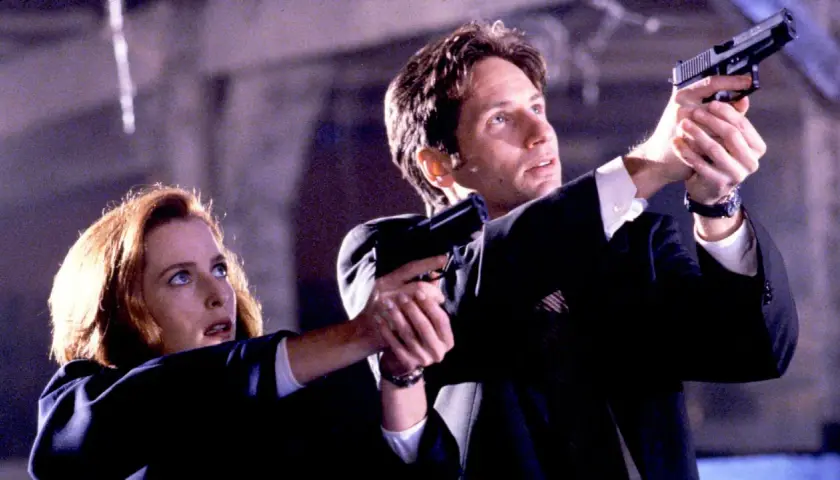 Z archiwum X: Scully i Mulder w akcji, celują z broni. Tajemnica czeka.