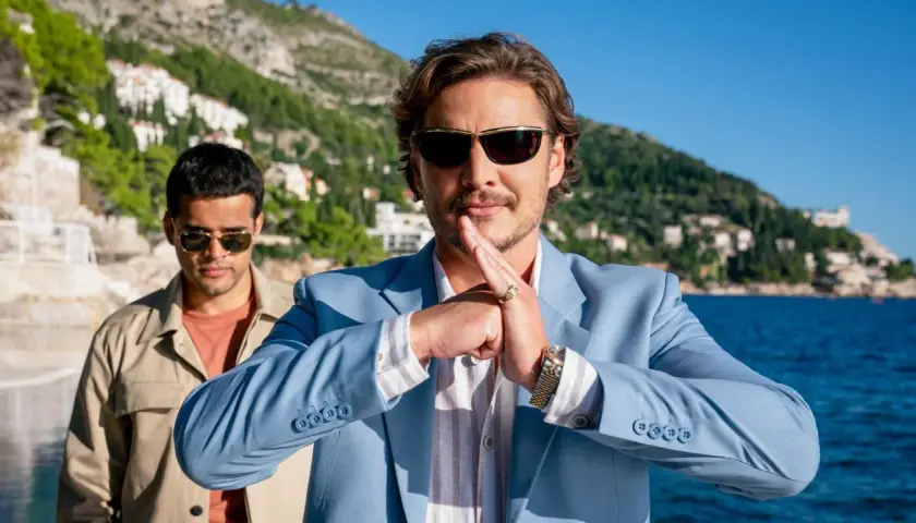Pedro Pascal w błękitnej marynarce, z dłońmi złożonymi w geście, jakby zapowiadał kolejne z jego filmów i seriali.