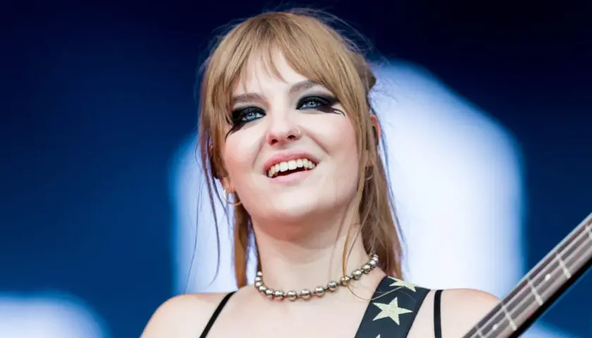 Victoria De Angelis z Måneskin, z charakterystycznym makijażem oczu, uśmiecha się podczas występu.