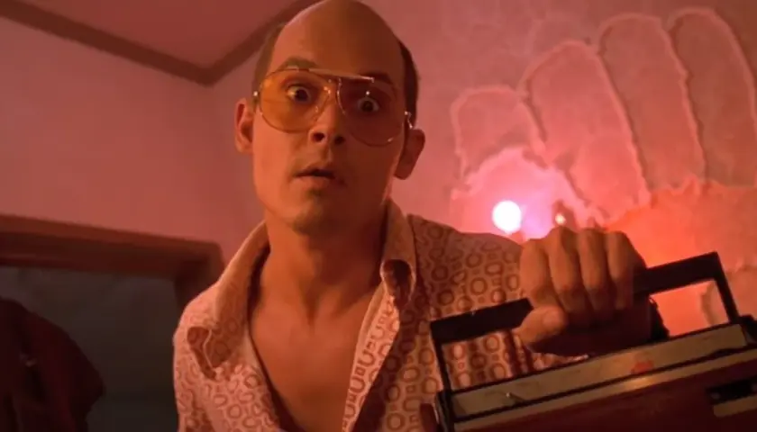 Raoul Duke z Las Vegas Parano, w okularach i wzorzystej koszuli, trzyma magnetofon.