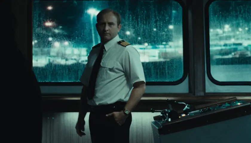 Kapitan w białej koszuli i krawacie stoi przy sterach statku. Scena z jednego z filmów Jana Holoubka.