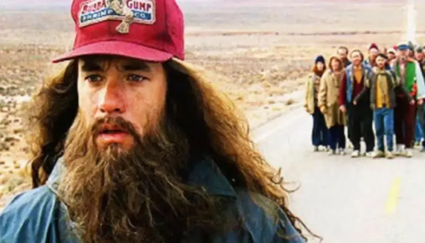 Forrest Gump (Tom Hanks) z brodą i czapką "Bubba Gump Shrimp Co." prowadzi grupę ludzi w podróży. Forrest Gump obsada w akcji.