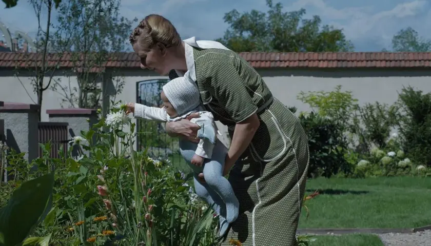 Kobieta w zielonej sukience pokazuje dziecku kwiaty. Scena jak z mądrych filmów wartych obejrzenia, pełna czułości i piękna natury.