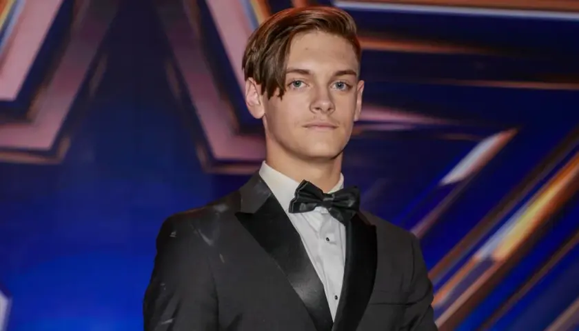 Młody mężczyzna w garniturze i muszce, gotowy na występ w Mam Talent 2024.